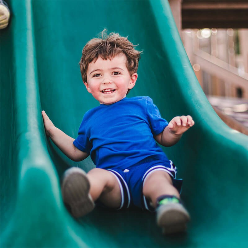 Baby coming down the slide smiling at the park